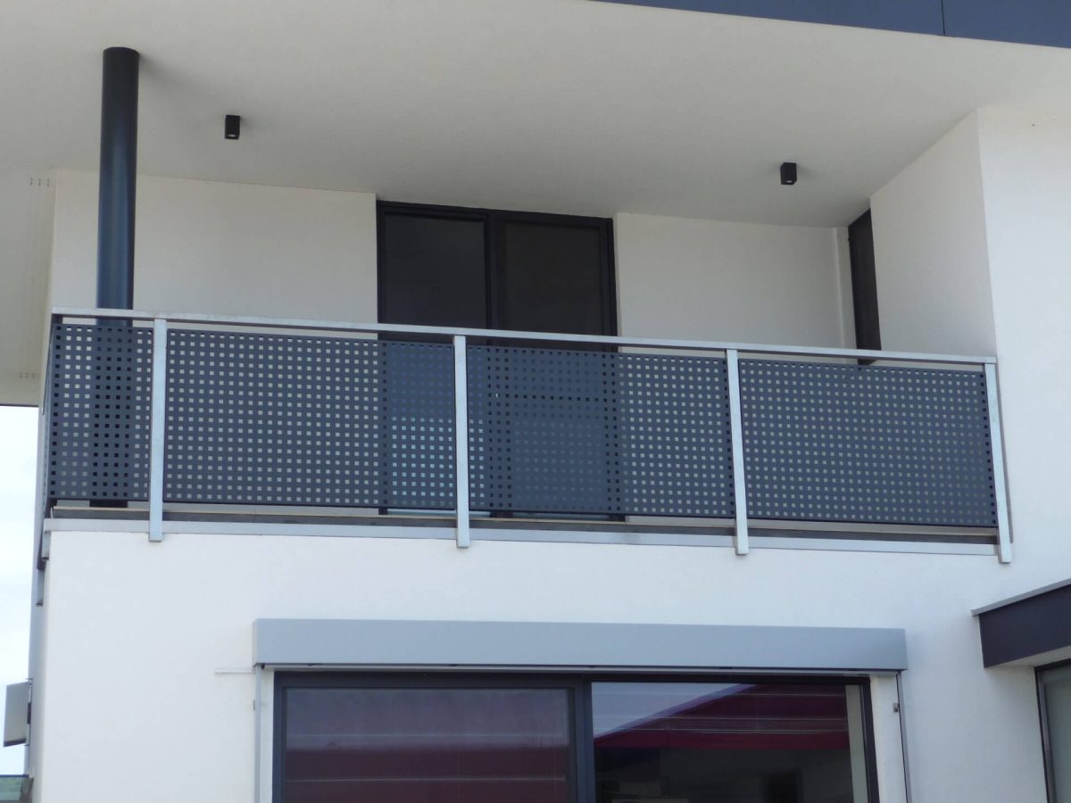 Modernes Balkongeländer aus Aluminium mit anthrazitfarbenem Lochblech, montiert an einem weißen Wohnhaus