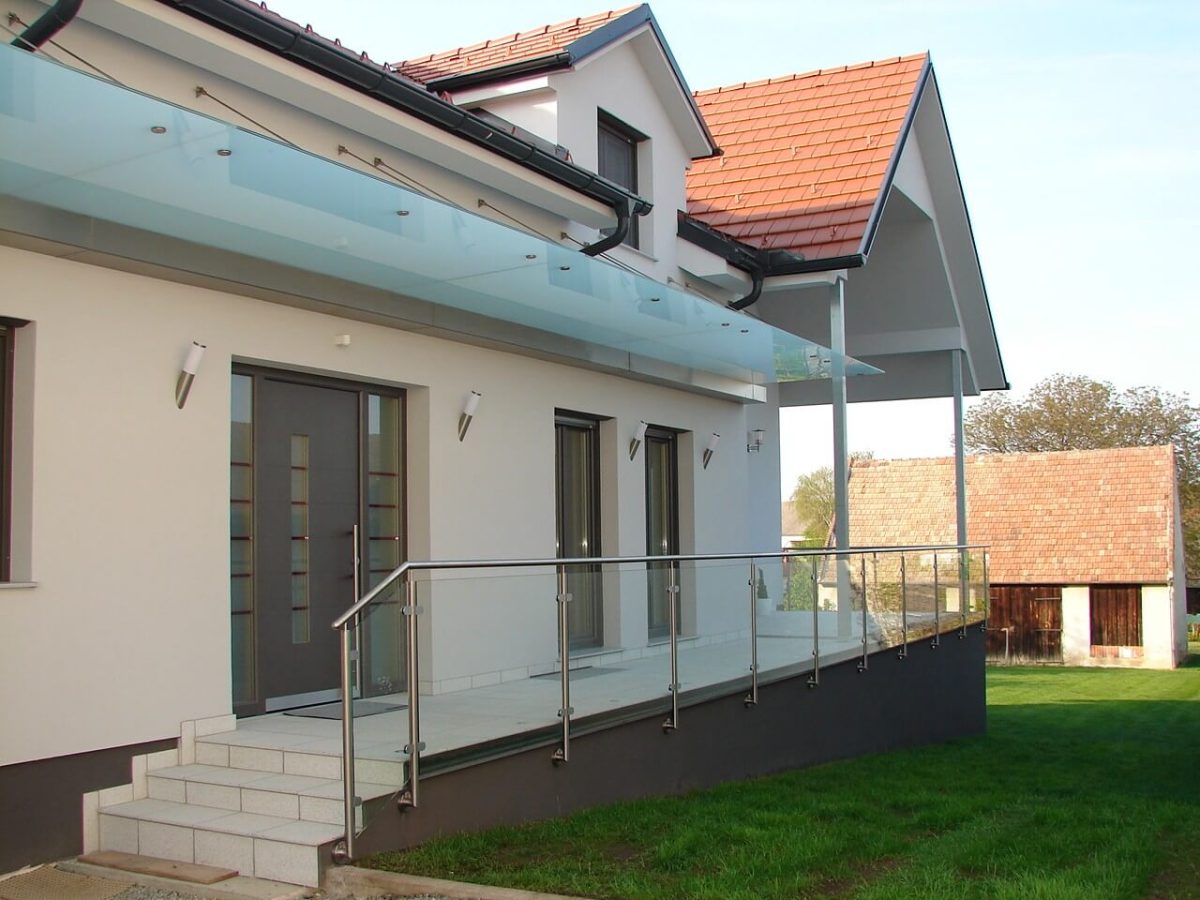 Modernes Terrassengeländer aus Glas mit Edelstahlpfosten und Überdachung aus Glas an einem Einfamilienhaus
