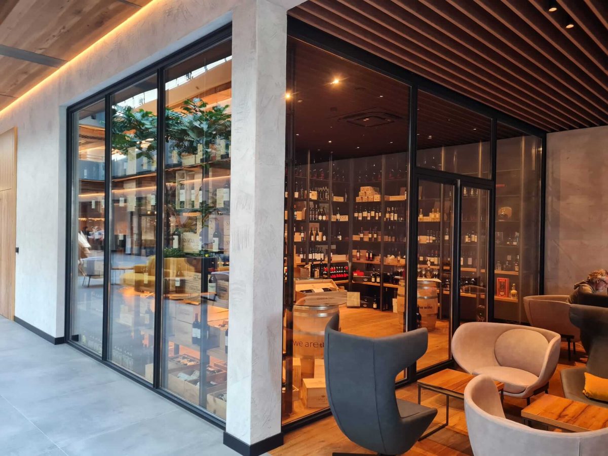 Moderne Weinlounge mit eleganter Glasfront, gemütlichen Sitzmöbeln und edler Weinauslage
