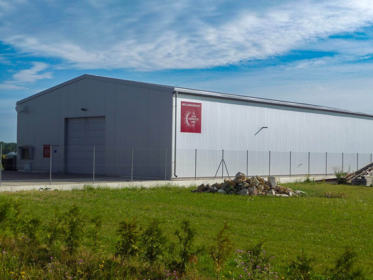 Moderne Industriehalle mit großem Sektionaltor und verzinktem Stahlzaun – ideal für Lagerung oder Produktion im Gewerbegebiet.