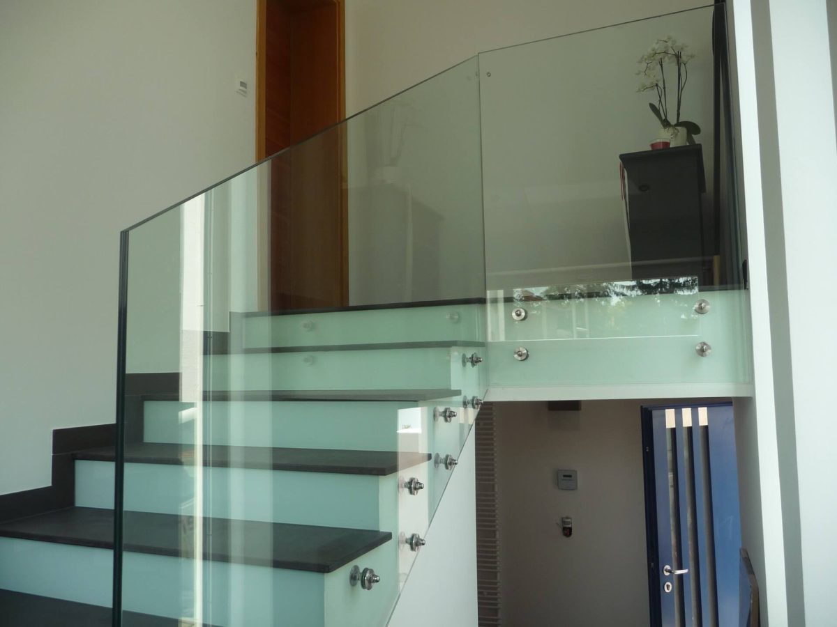 Moderne Innenstiege mit satiniertem Glasgeländer und dunklen Trittstufen in einem hellen Wohnbereich