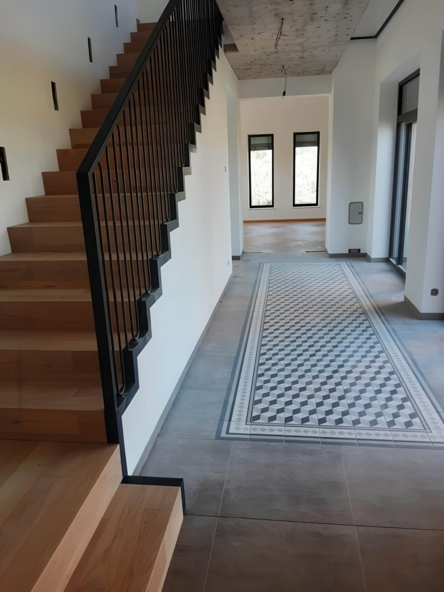 Elegante Innentreppe mit klarer Linienführung: massive Holzstufen kombiniert mit einem Zickzack-Stahlwangenprofil und einem modernen senkrechten Flachstahlgeländer – ideal für stilvolle Wohnräume mit Designanspruch