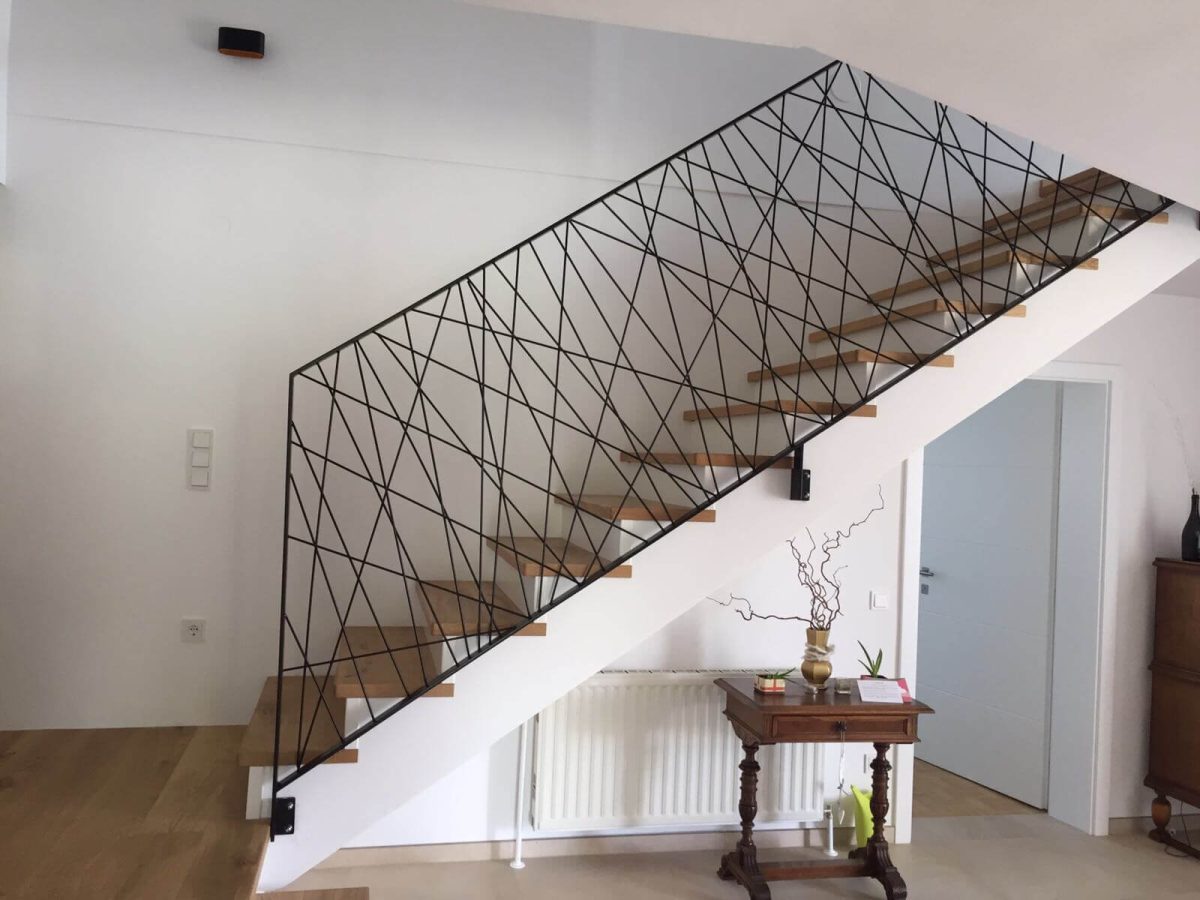 Innenraumgeländer aus schwarzem Flachstahl mit kunstvoll versetzten Diagonalstäben – filigranes Design mit klarer Linienführung für moderne Wohnräume