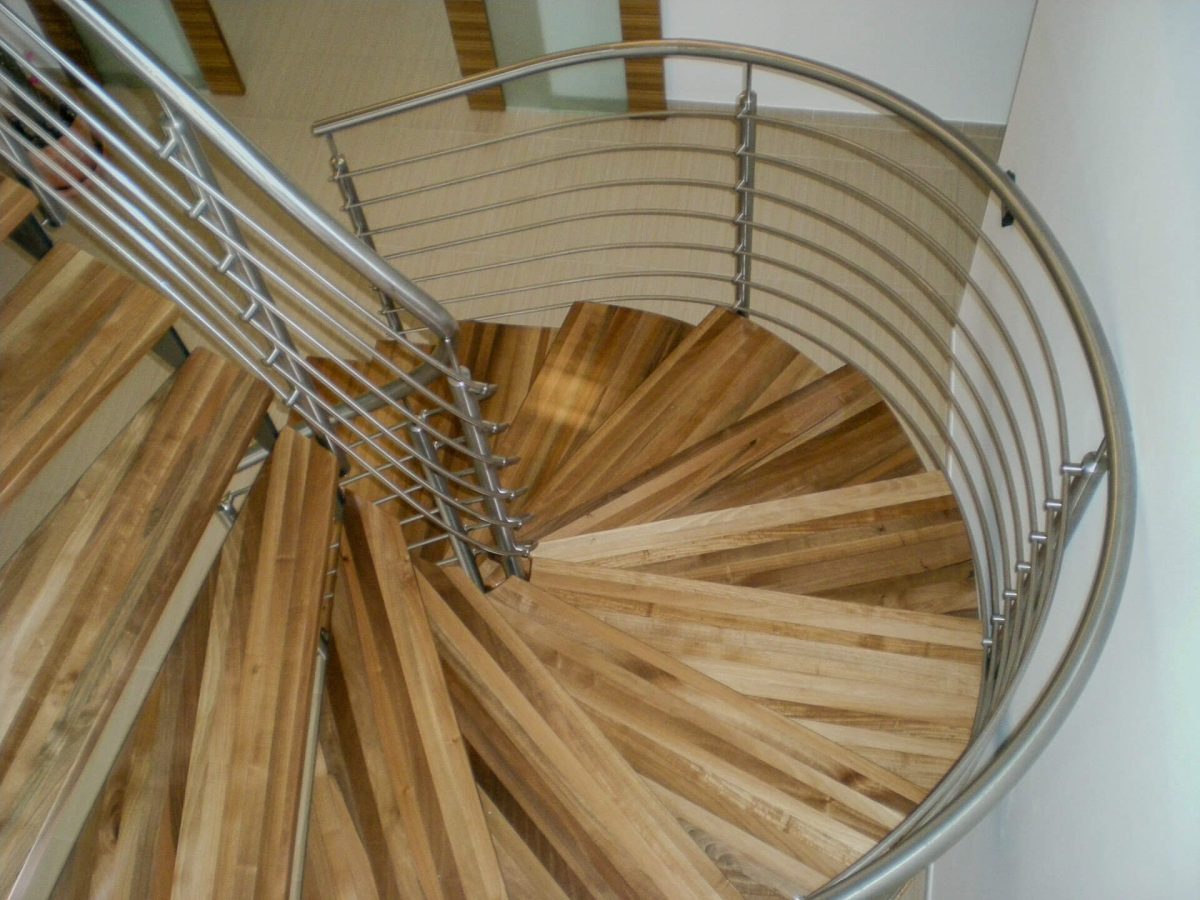 Moderne Wendeltreppe mit Holzstufen und gebogenem Edelstahlgeländer, ideal für elegante Innenarchitektur.