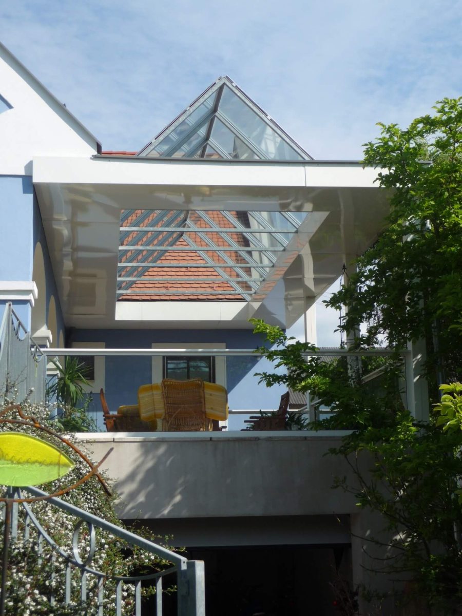 Moderne Glasüberdachung einer Terrasse mit Pultdach und Glasgeländer, schafft lichtdurchfluteten Außenbereich.