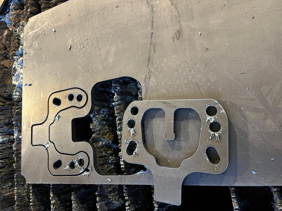 Zwei aus einer Stahlplatte herausgetrennte Metallteile mit präzisen Konturen und Bohrungen nach Plasmaschneidverfahren