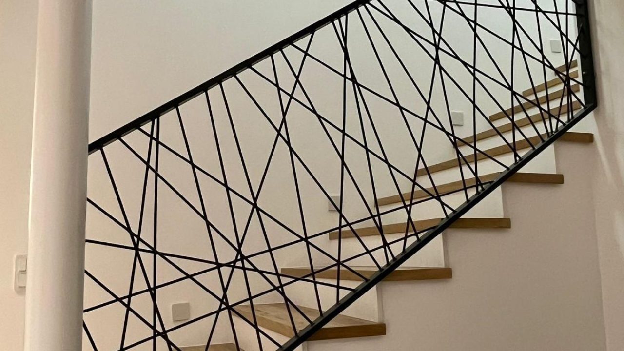 Schwarzes Treppengeländer mit unregelmäßigem Strebenmuster an einer Holztreppe in einem modernen Wohnraum