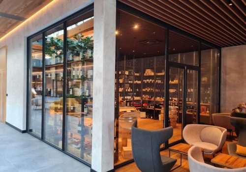 Innenaufnahme einer stilvollen Weinlounge mit Glastrennwand und gemütlichen Sitzgelegenheiten